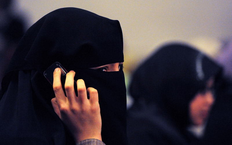 A woman wearing a burqa talks on a mobil
